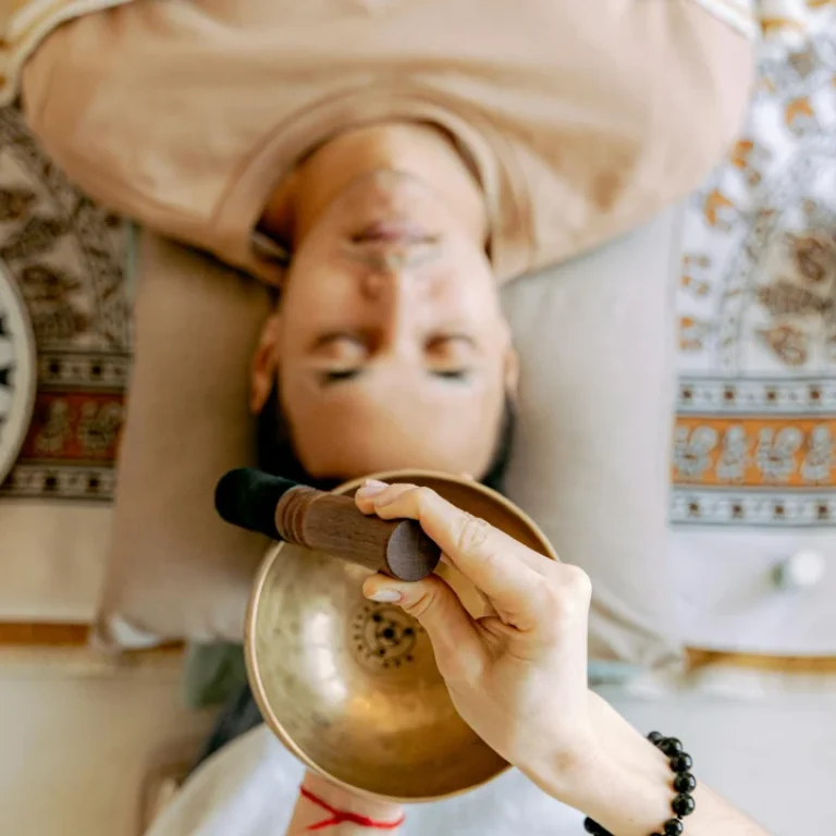 Man receiving sound healing whilst lying on his back which is an alternative holistic energy healing technique